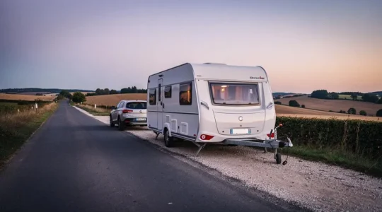 Caravane blanche à l'arrêt sur une route de campagne au crépuscule, symbolisant un vide de couverture d'assurance